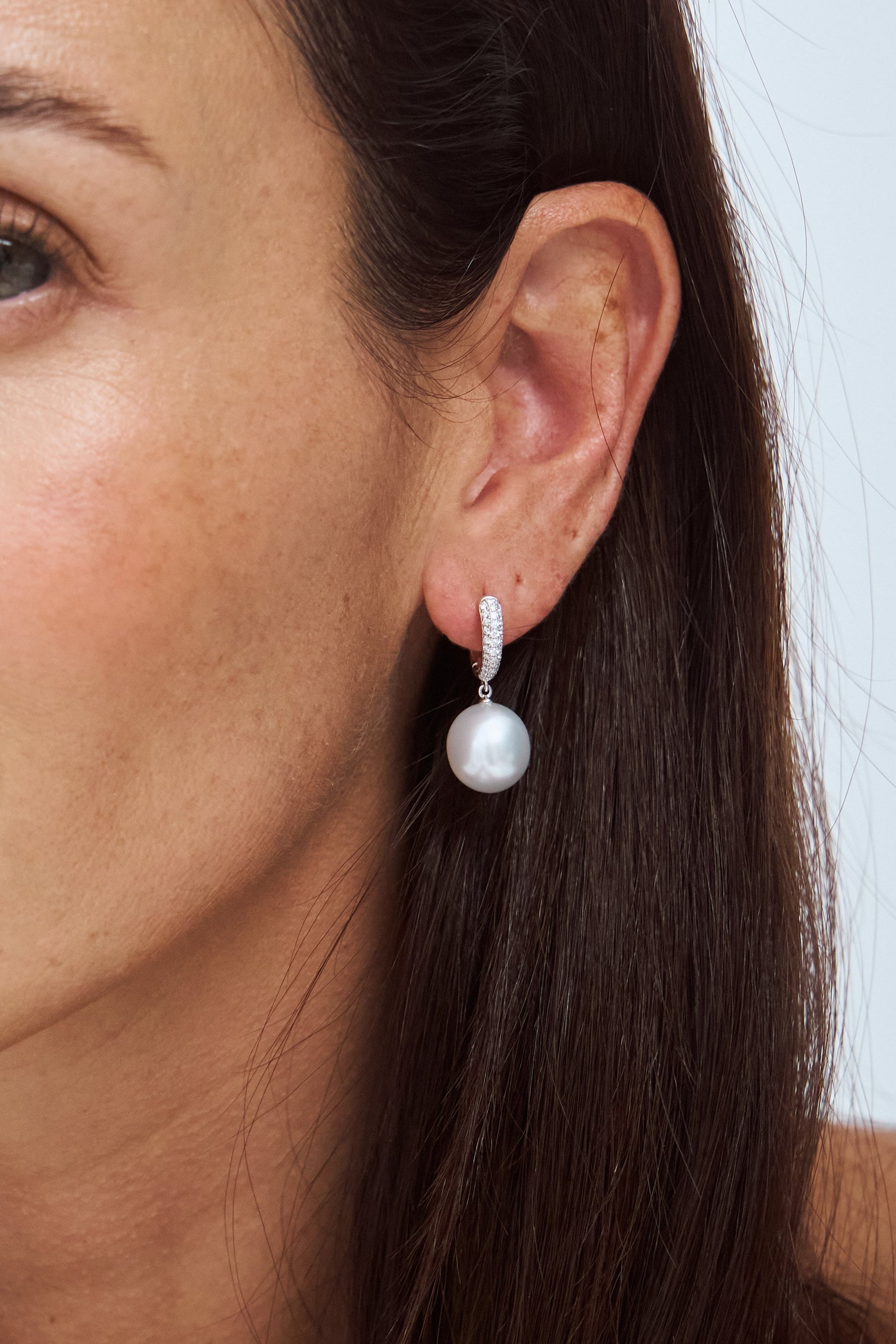 Model wearing Autore Serenity Pave Tapered Huggies in 18kt white gold and white diamonds