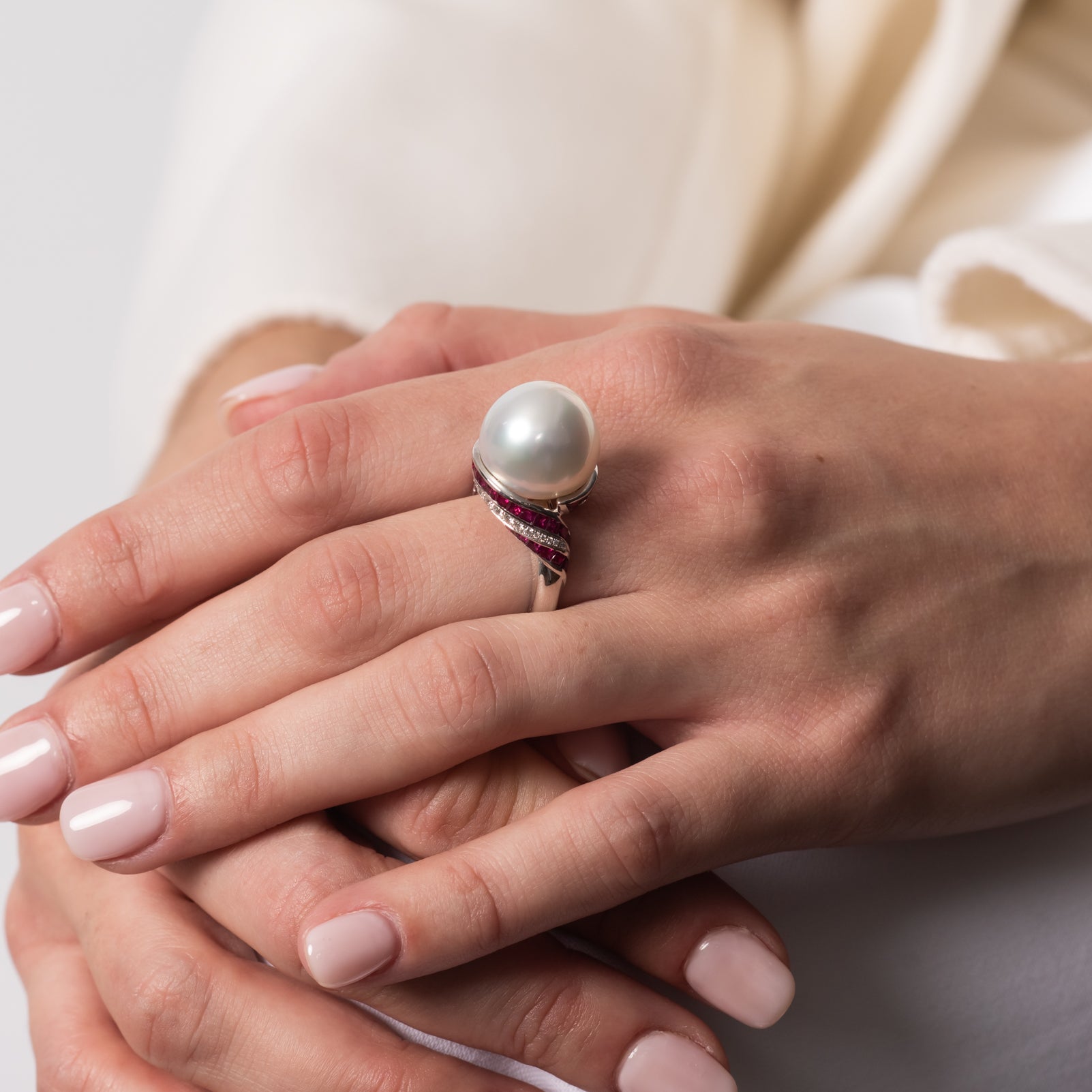 Close-up of a model's hands wearing the Autore South Sea pearl ring with ruby and diamond details in 18kt white gold