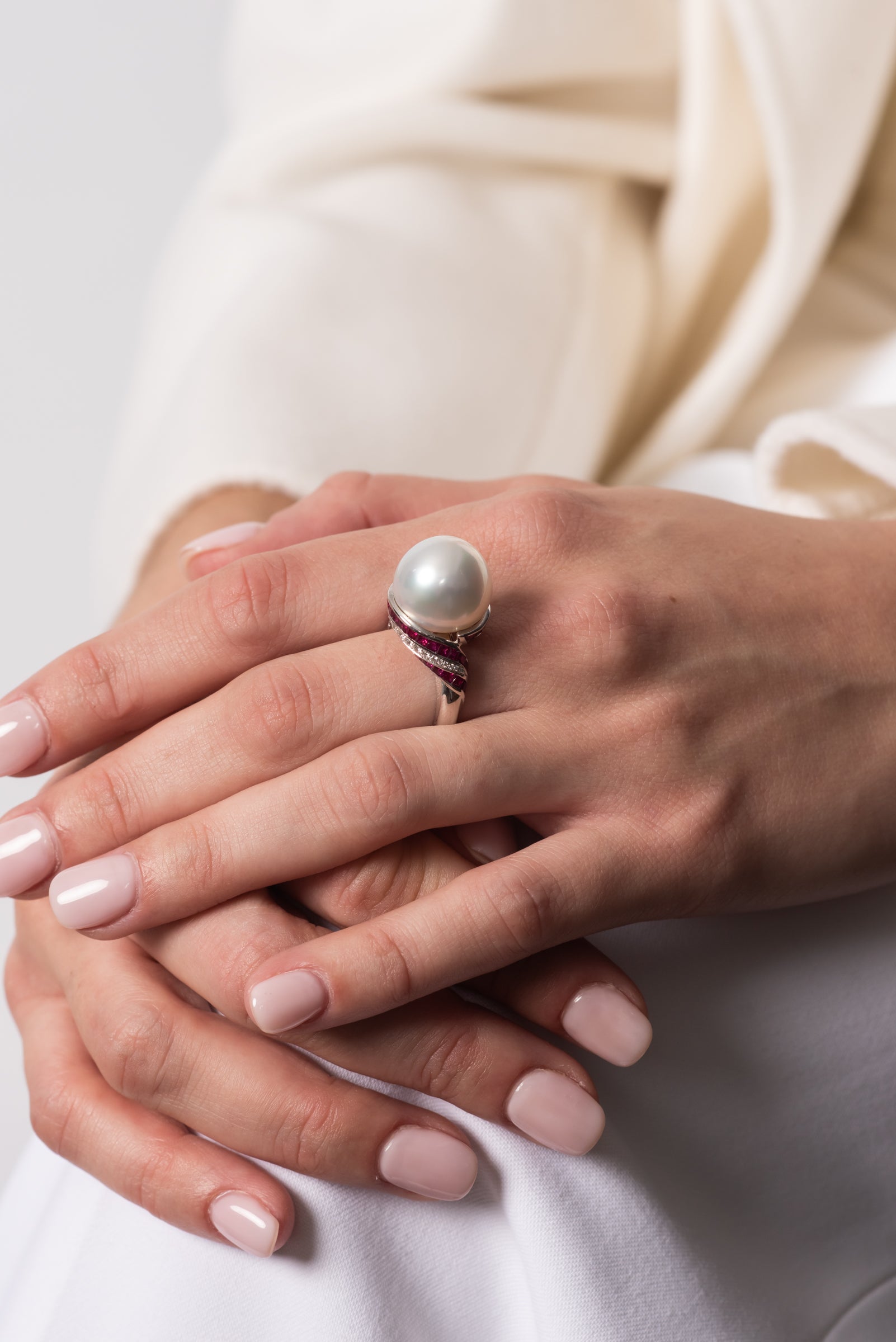 Close-up of a model's hands wearing the Autore South Sea pearl ring with ruby and diamond details in 18kt white gold